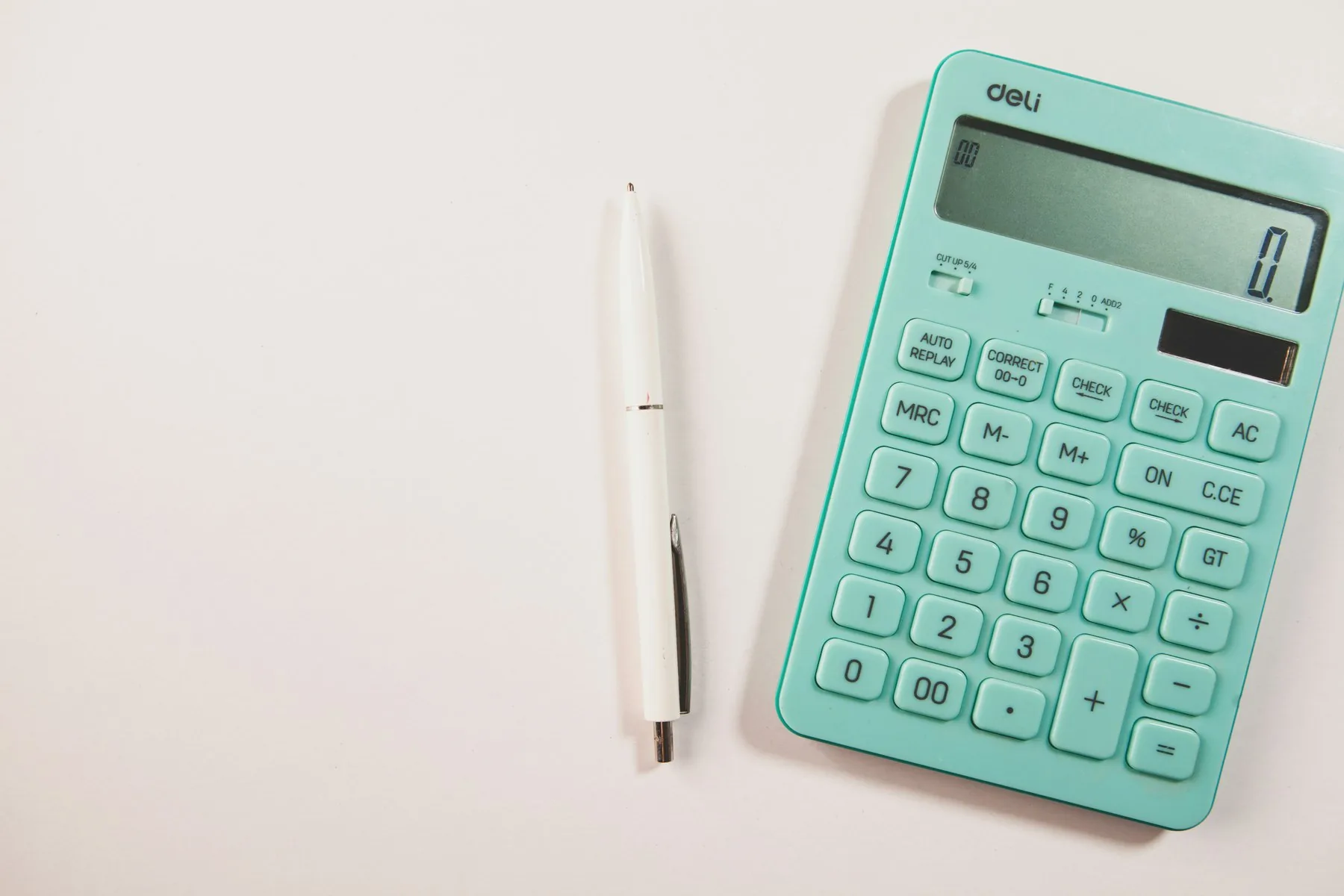 A calculator and pen on a white desk